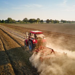 Tractor working in agricultural field, cultivating and plowing dry soil Tractor working in agricultural field, cultivating and plowing dry soil